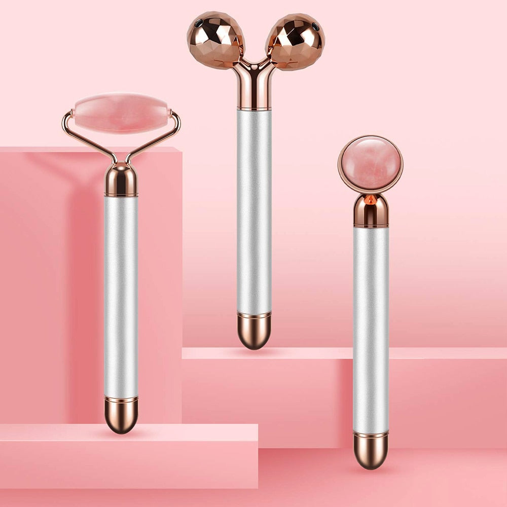 Electric facial roller with three rose-quartz heads displayed on pink pedestal, showing attachments and size.