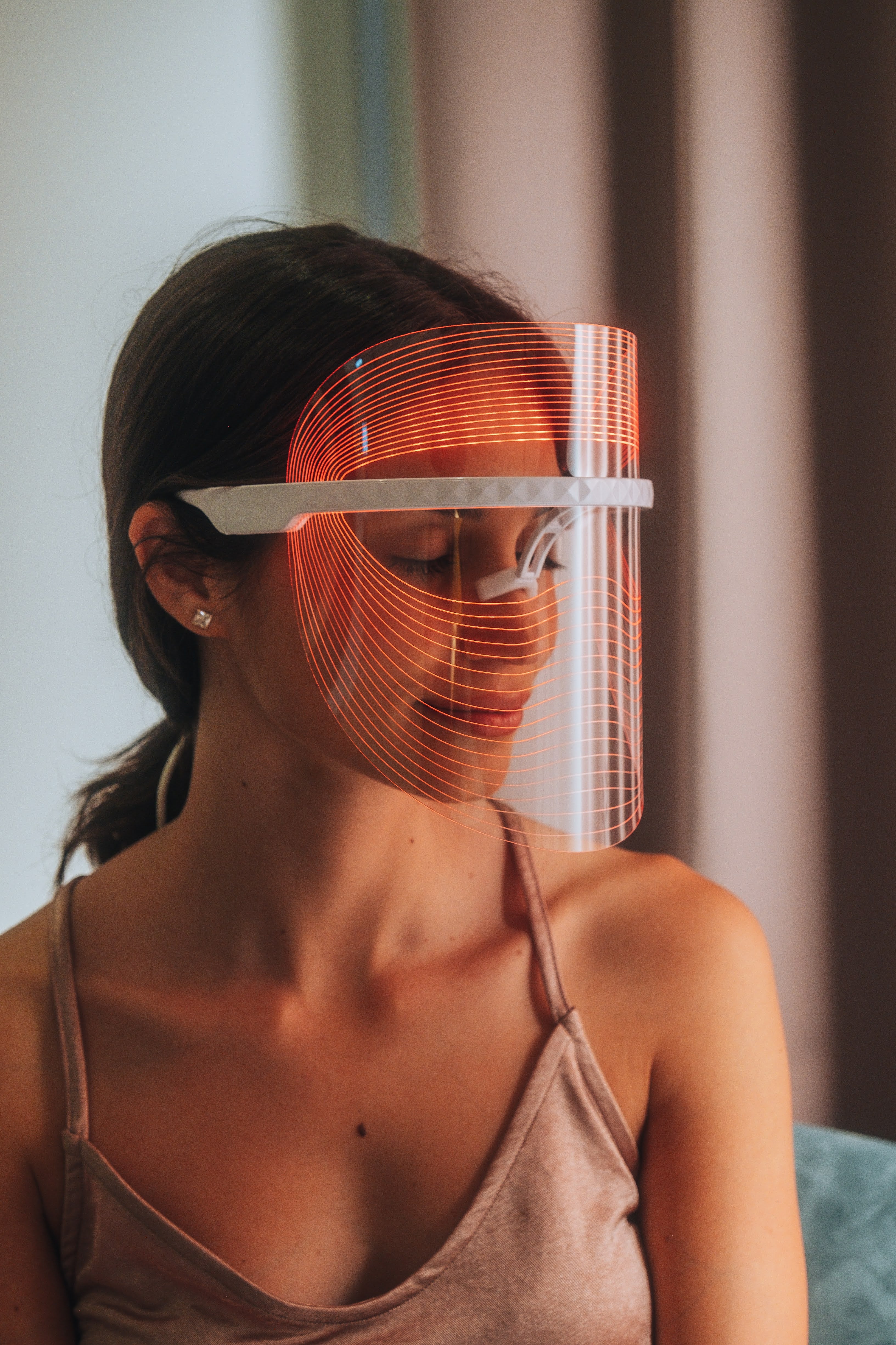 Model using COCOON SKIN LED face mask in orange light mode; full-face coverage, front view