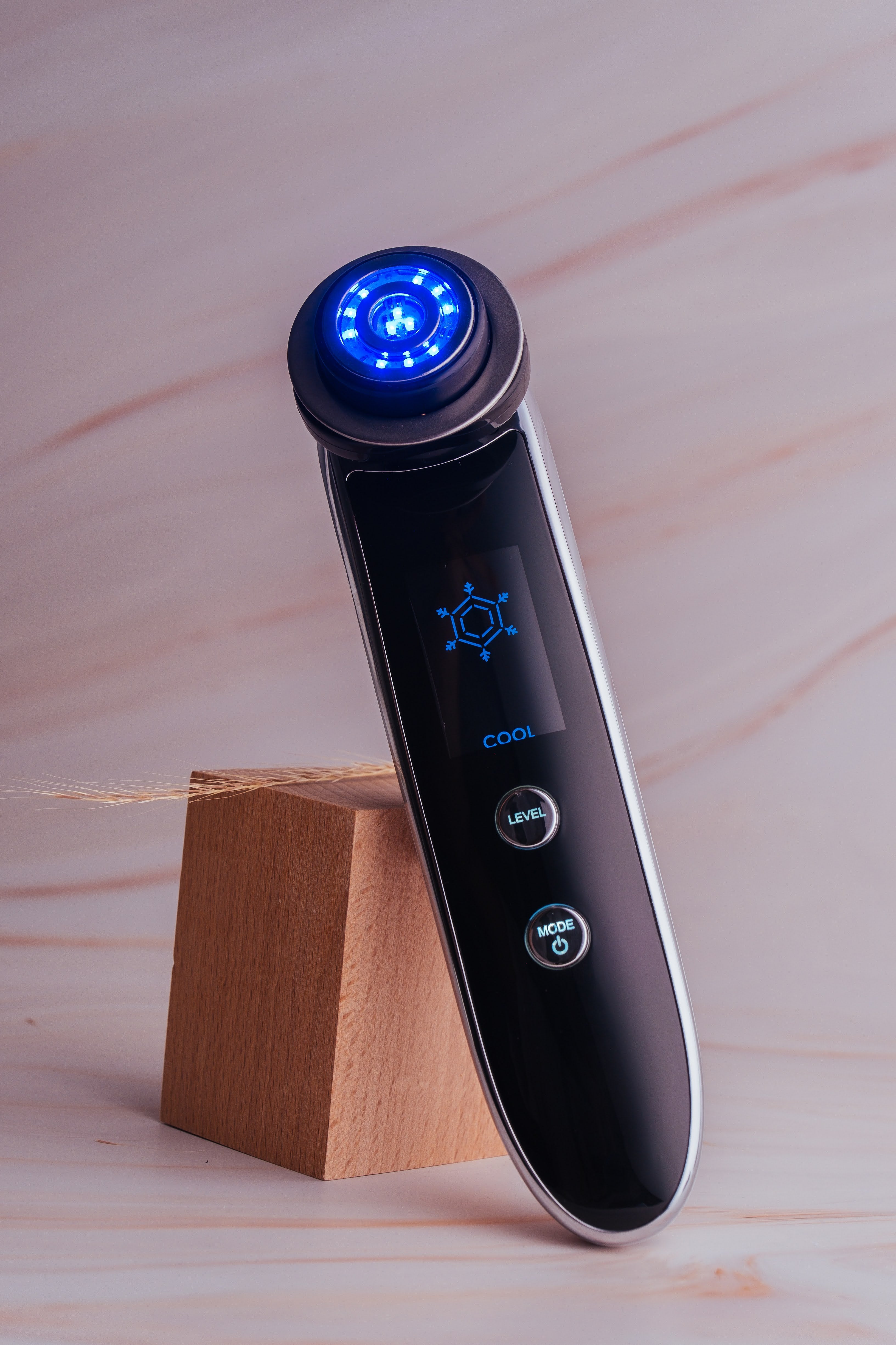 Fav Naomi Cocoon RF wand standing upright with blue LED ring on wooden base.