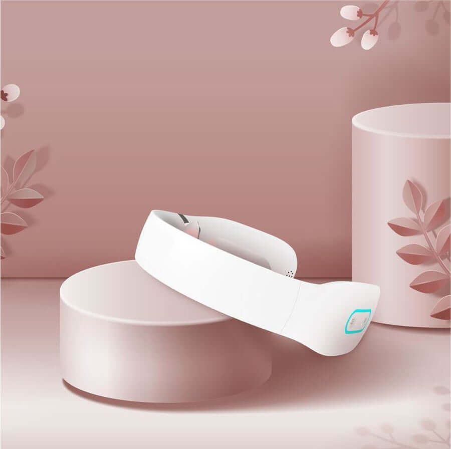 White K3 neck massager on blush pedestal with spa props, angled view showing pads and LED indicator